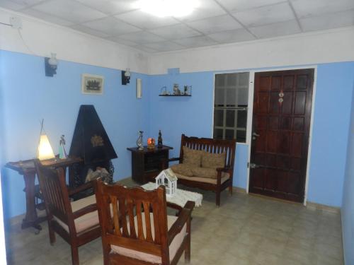 una sala de estar con paredes azules y sillas de madera. en Lo de Lili en Puerto Madryn