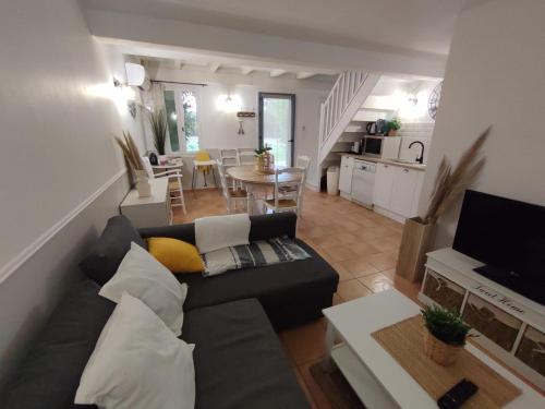 a living room with a black couch and a kitchen at Mas de la Tour Carbonnière in Aigues-Mortes