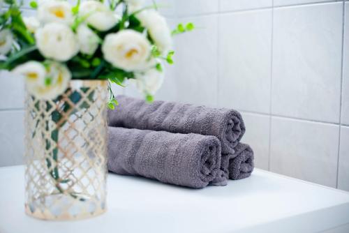 a vase of white flowers and towels on a counter at Apartman Karla in Sinj