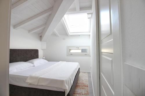 a white bedroom with a bed and a window at Villa Benatti in Carpi