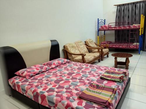 ein Schlafzimmer mit einem Bett und Stühlen in einem Zimmer in der Unterkunft Taiping Centre Point Suite in Taiping