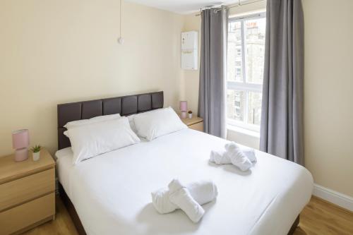 ein Schlafzimmer mit einem großen weißen Bett mit Handtüchern darauf in der Unterkunft The Tower Bridge Cosy Flat in London