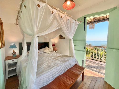 a bedroom with a canopy bed with a view of the ocean at Blow Show Casa III Guest House in Ilhabela