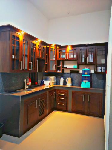 a large kitchen with wooden cabinets and a yellow floor at SHARAH Beach Resort in Addalachenai