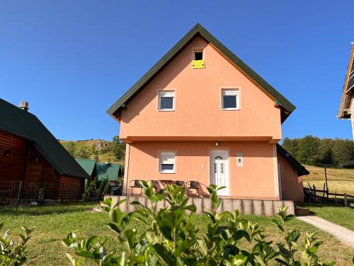 a house with a yellow sign on the side of it at Guest House Happy in Žabljak