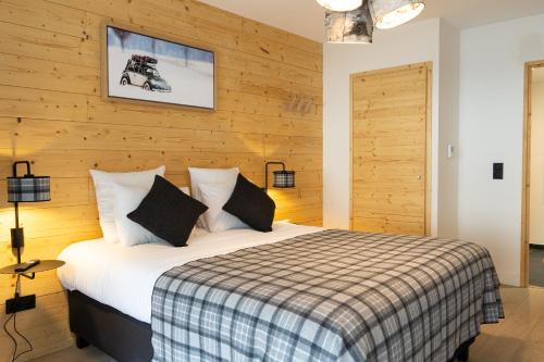 ein Schlafzimmer mit einem Bett mit einer Holzwand in der Unterkunft Roches Blanches by Daddy Pool - TERRESENS in Combloux