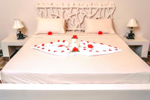 a white bed with red roses on it at RoRi Private Luxury Villas in Bwejuu