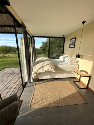 a bedroom with a bed and a large window at Chacra La Recompensa Glamtainer in Paysandú