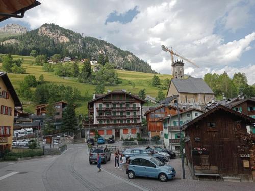 a town with cars parked on a street with a mountain at Cèsa Viosadea in Campitello di Fassa