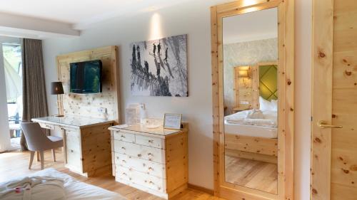 a bedroom with a bed and a desk and a mirror at Hotel Kesslermühle in Hinterzarten