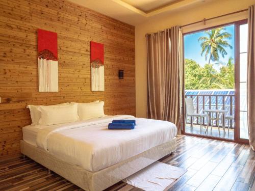 a bedroom with a large bed and a balcony at Thundi Village & Spa in Maalhos