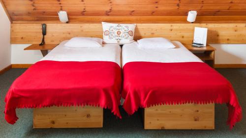 two beds in a room with red blankets at Willa Jordanówka in Czorsztyn
