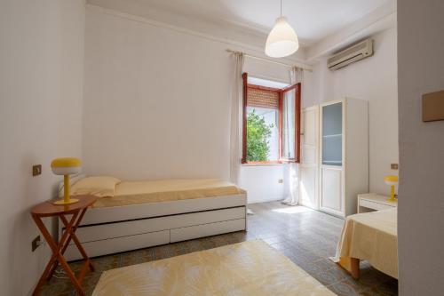 ein weißes Schlafzimmer mit einem Bett und einem Fenster in der Unterkunft Maison Adriana con giardino - 10 minuti dal Poetto e dal Parco Molentargius in Quartu SantʼElena