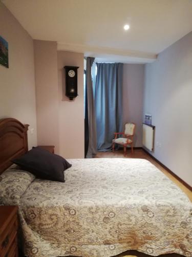1 dormitorio con 1 cama grande y reloj en la pared en Casa Güelito, en Candás