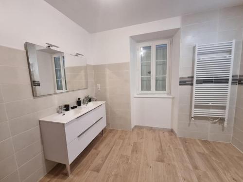 La salle de bains blanche est pourvue d'un lavabo et d'un miroir. dans l'établissement Chez Cédric et Mélissa maison Lou Milhòc en Béarn, 