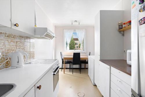 a white kitchen with a table and a dining room at Sentralt og romslig leilighet in Drammen