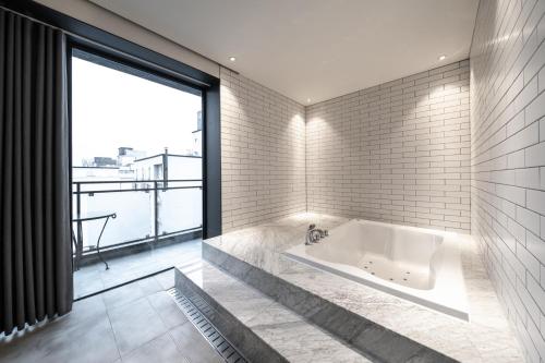 uma banheira na casa de banho com uma grande janela em Jeonju Jazz Around Hotel em Jeonju