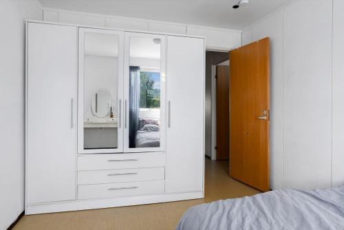um quarto com um armário branco com um espelho em Sentralt og romslig leilighet em Drammen