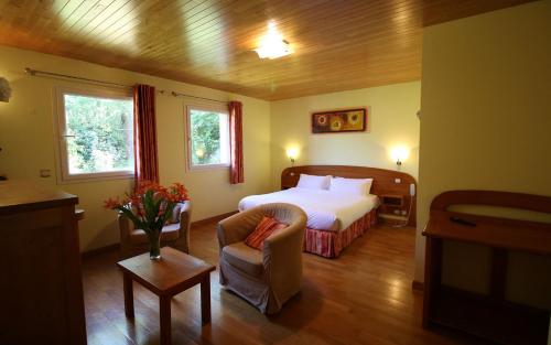 une chambre d'hôtel avec un lit et une chaise dans l'établissement Logis Hôtel-restaurant La Mère Biquette, à Saint-Pons