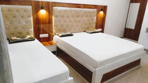 two beds in a room with white sheets at SHREE ATITHI HIGHWAY HOTEL in Ābu Road