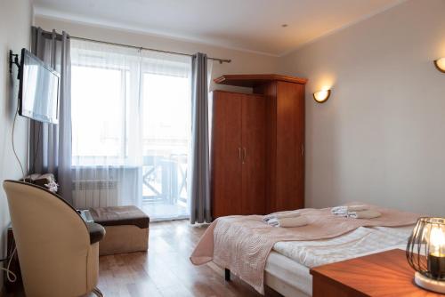 um quarto com uma cama, uma mesa e uma janela em Willa Maja em Ciechocinek