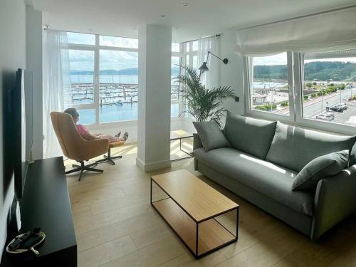 a woman sitting in a chair in a living room at MALECON 47 Apartamento reformado en primera linea in Muxia