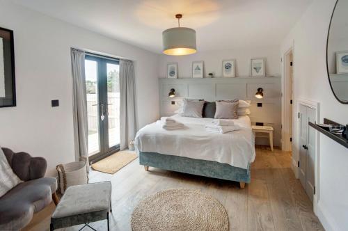 um quarto branco com uma cama e uma cadeira em Seaside House em Beadnell