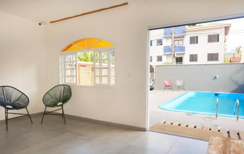 a swimming pool in a room with chairs and a window at Sea Wolf Hostel - Lagoa da Conceição in Florianópolis
