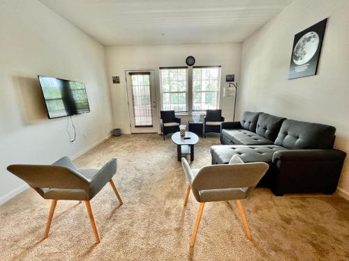 ein Wohnzimmer mit einem schwarzen Sofa und Stühlen in der Unterkunft Waterfront escape 