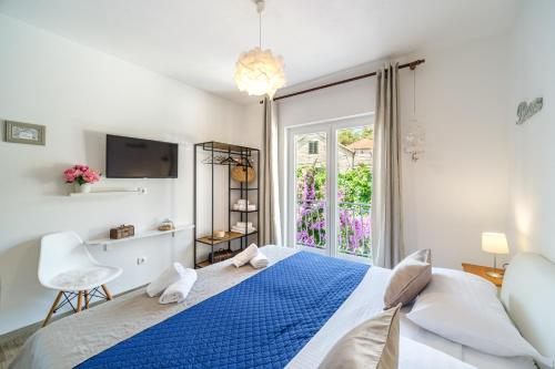 een witte slaapkamer met een blauw bed en een raam bij Rooms Anna in Milna