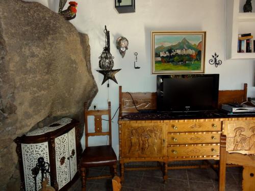 een woonkamer met een tv en een houten dressoir bij Castillo Lanzarote Villa 1 - Sleep in a Volcanic Cave in Tías