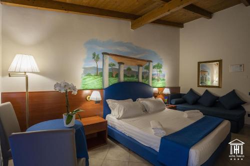 a bedroom with a blue bed and a couch at Hotel Tempio in Lago Patria