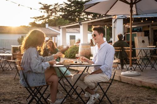 un homme et une femme assis à une table avec un verre de vin dans l'établissement Huttopia Ars-en-Ré, à Ars-en-Ré