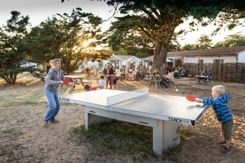 dos niños jugando ping pong en una mesa de ping pong en Huttopia Ars-en-Ré, en Ars-en-Ré