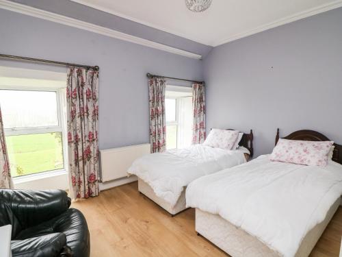 two beds in a room with a couch and a window at The Bride Valley Farmhouse 