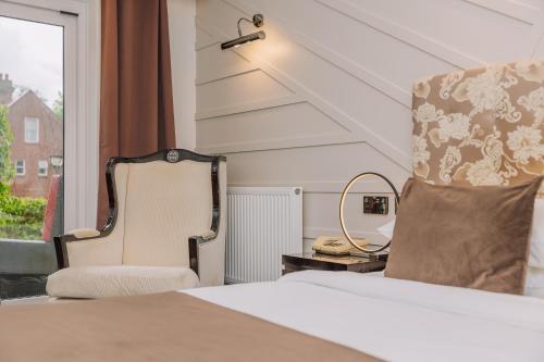 a bedroom with a bed and a chair and a window at Muthu Belstead Brook Hotel in Ipswich