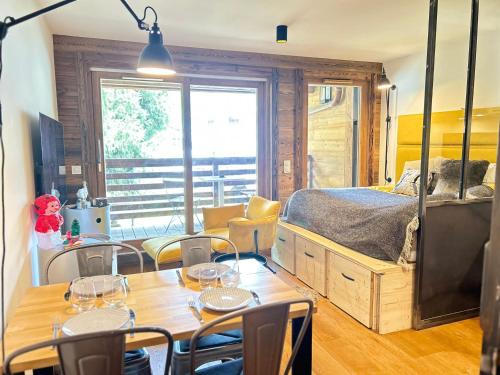 une pièce avec une table et un lit et une table et des chaises dans l'établissement Studio neuf au cœur des Gets avec SPA, proche des pistes, parking et wifi inclus - FR-1-623-34, aux Gets