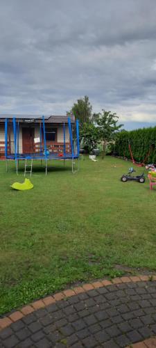 a yard with a house and a playground at Domki Monika in Sarbinowo