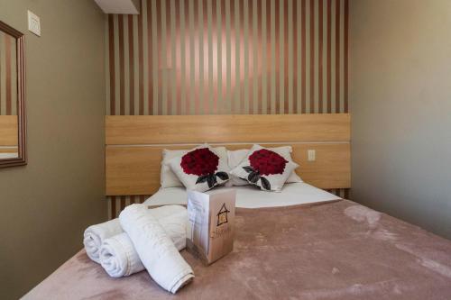 a bedroom with a bed with flowers and towels at Hotel Morada Del Este in Canoas