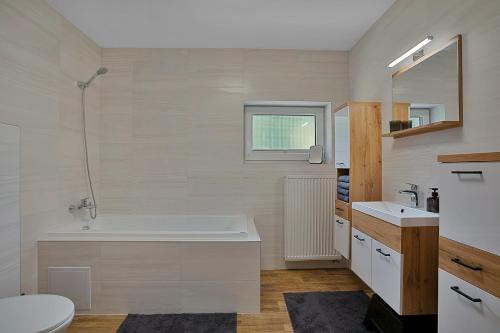 a bathroom with a tub and a toilet and a sink at Krušné Apartmány in Loučná pod Klínovcem