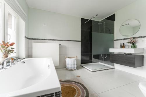 een witte badkamer met een wastafel en een spiegel bij Vakantiewoning 't Hovenshuis in Kinrooi