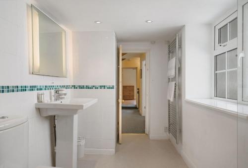 a white bathroom with a sink and a mirror at The Boy's Cottage in Portreath