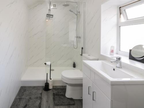 a white bathroom with a toilet and a sink at Jasmine Villa in Llandudno