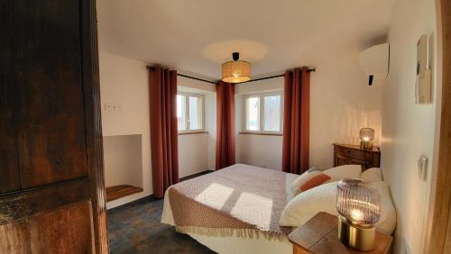 Schlafzimmer mit einem Bett, einem Tisch und Fenstern in der Unterkunft Entre ciel et mer dans la Citadelle in Calvi