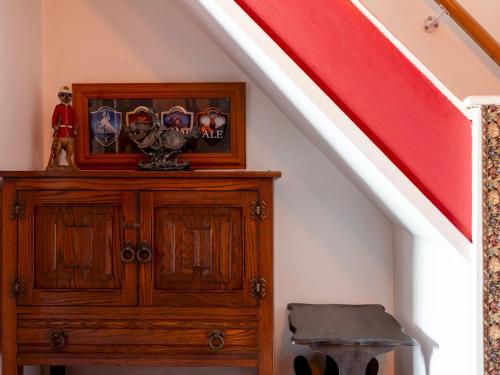 a wooden cabinet under a staircase with a red stair railing at Pass the Keys Cosy Cottage with Fireplace in Bridgwater
