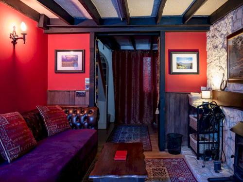 a living room with a couch and red walls at Pass the Keys Cosy Cottage with Fireplace in Bridgwater