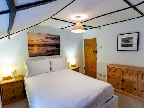 a bedroom with a white bed and wooden cabinets at Pass the Keys Cosy Cottage with Fireplace in Bridgwater