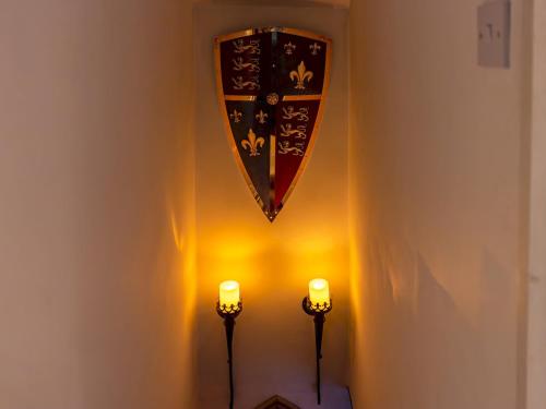 a shield hanging on a wall with two candles at Pass the Keys Cosy Cottage with Fireplace in Bridgwater