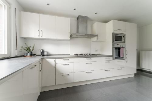 una cocina blanca con armarios y electrodomésticos blancos en Vakantiewoning 't Hovenshuis en Kinrooi
