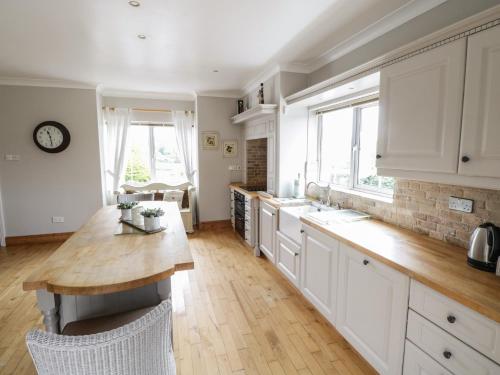 a kitchen with white cabinets and a wooden counter top at The White House in Drumshanbo